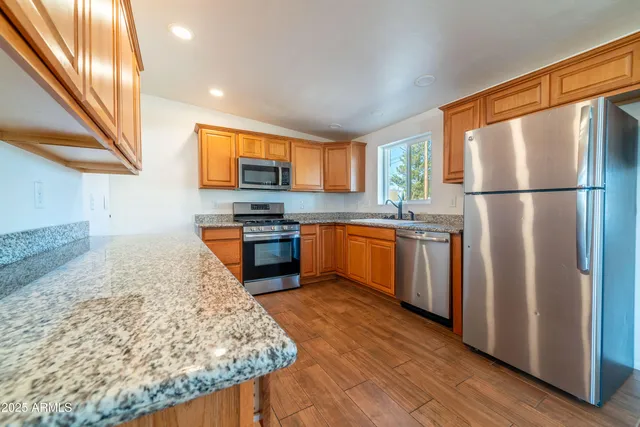 a kitchen with stainless steel appliances granite countertop a refrigerator a stove and a sink