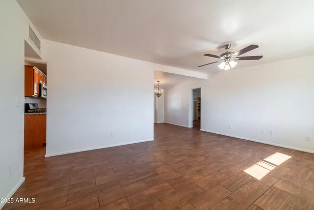 a view of an empty room with window and a ceiling fan