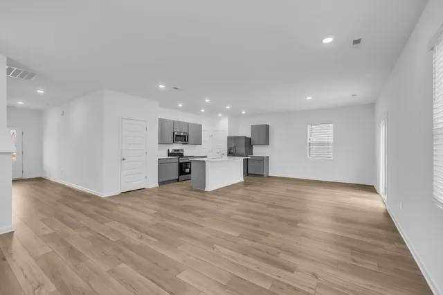a view of kitchen with kitchen island wooden floor center island and stainless steel appliances