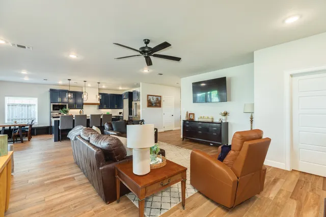 a living room with furniture a flat screen tv and kitchen view
