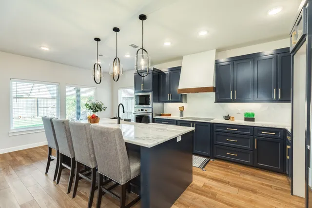 a large kitchen with granite countertop a stove a sink a dining table and chairs