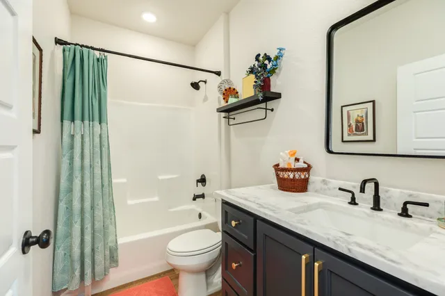 a bathroom with a granite countertop sink a toilet and shower