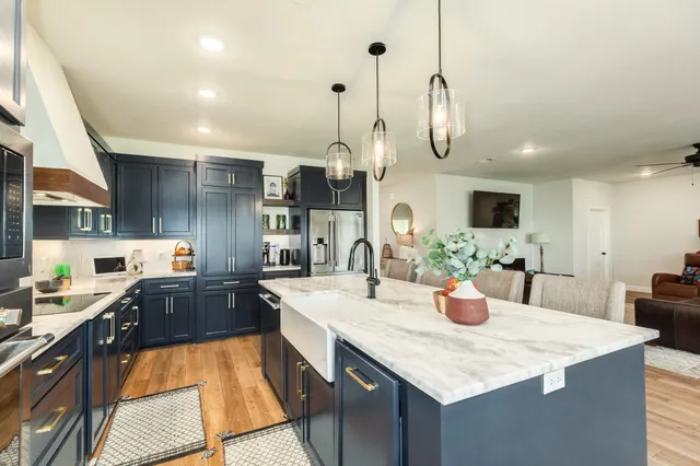 a kitchen with stainless steel appliances kitchen island granite countertop a sink a stove top oven a chimney and a center island