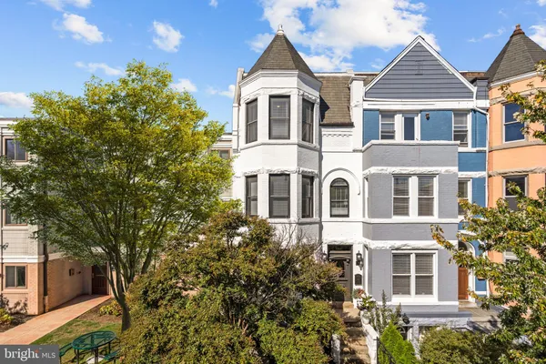 a view of a big yard in front of a brick house with large windows