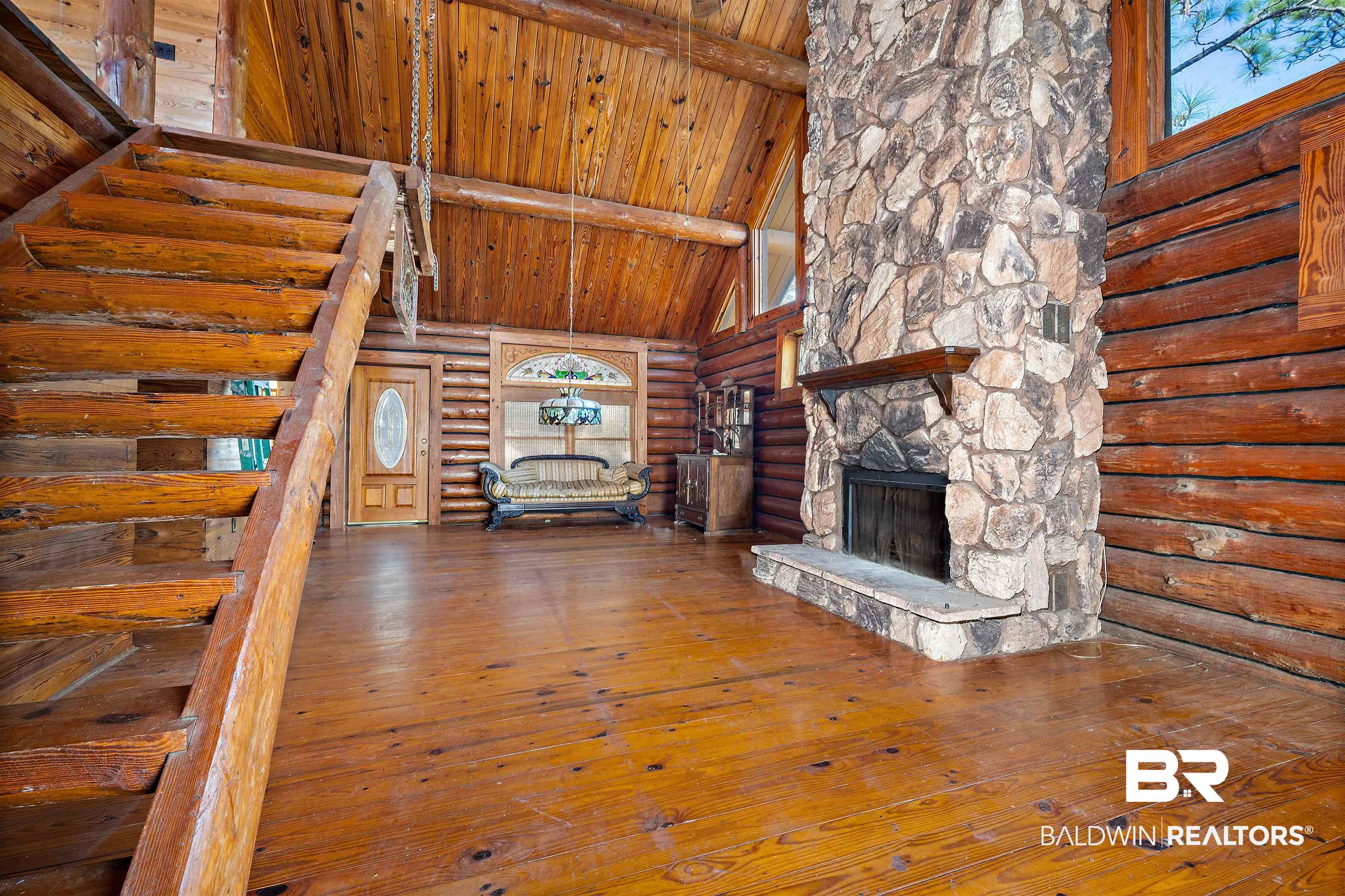 11236 Wren Avenue Fairhope, AL 36532 - Photo 6 of 35 Unfurnished living room with log walls, high vaulted ceiling, wood-type flooring, stairs, and a wood ceiling with exposed beams