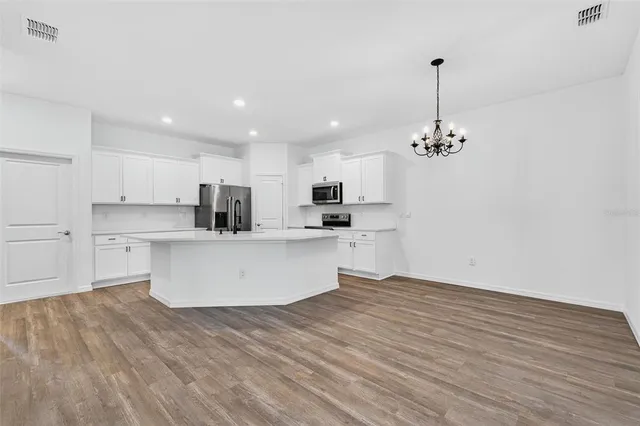 a view of a chandelier in big room with wooden floor