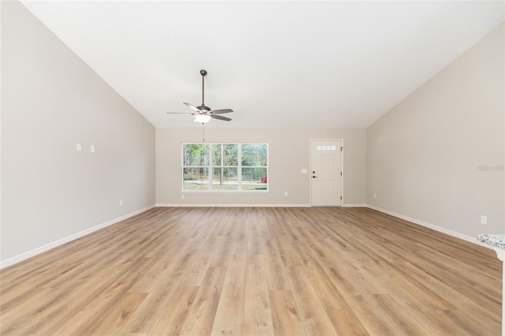 5796 Southwest 124th Ter Road Ocala, FL 34481 - Photo 8 of 63 an empty room with wooden floor chandelier and windows