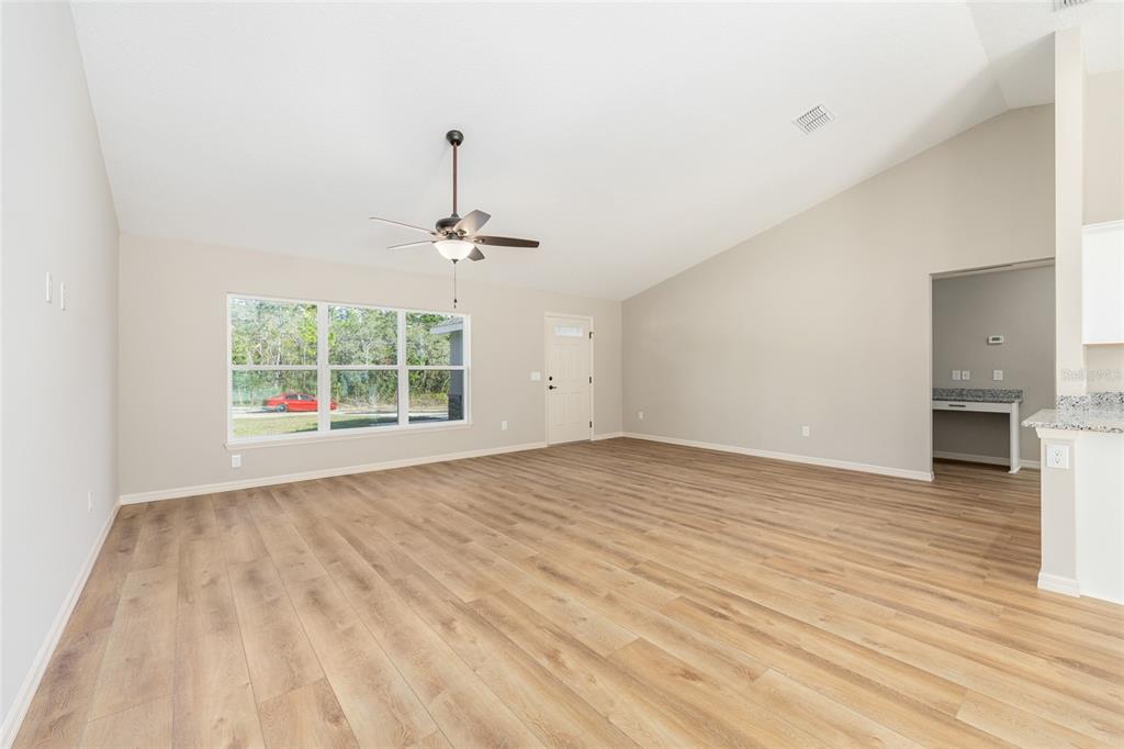 5796 Southwest 124th Ter Road Ocala, FL 34481 - Photo 9 of 63 an empty room with wooden floor chandelier and windows