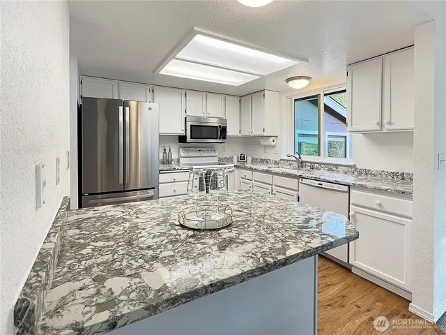 a kitchen with kitchen island granite countertop a sink cabinets and stainless steel appliances
