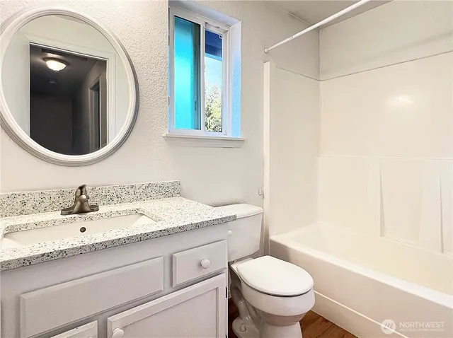 a bathroom with a granite countertop toilet sink and mirror