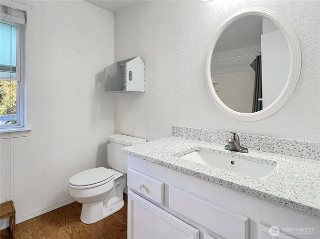 a bathroom with a granite countertop toilet sink and mirror