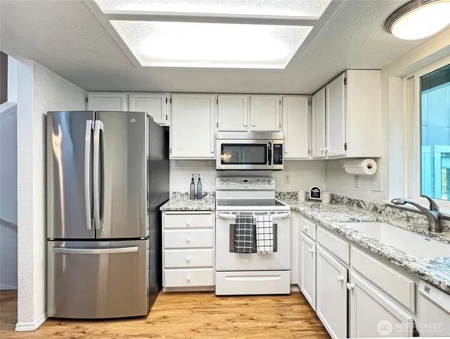 a kitchen with a refrigerator sink and white cabinets