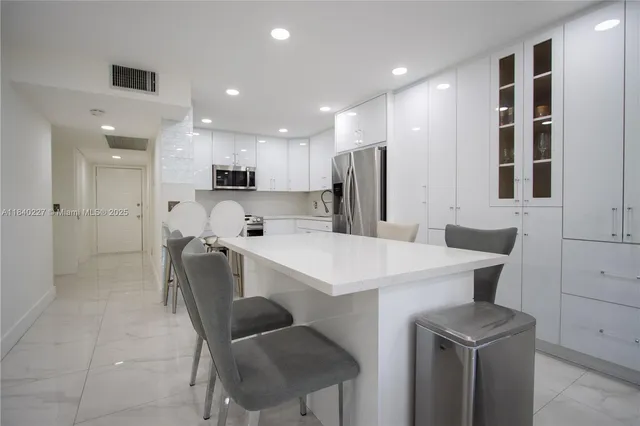 a kitchen with a dining table chairs refrigerator and cabinets