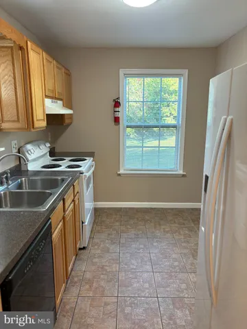 a kitchen with a sink a stove top oven and a refrigerator
