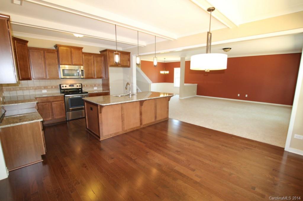 7140 Meyer Road, Unit 309 Fort Mill, SC 29715 - Photo 7 of 16 a kitchen with stainless steel appliances granite countertop a sink a stove and a wooden floor