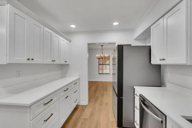 a kitchen with granite countertop white cabinets and refrigerator