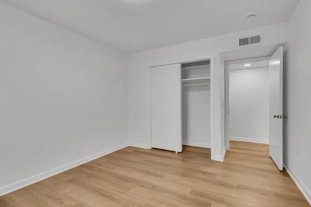a view of an empty room with wooden floor and closet