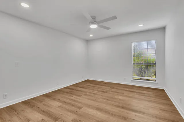 an empty room with wooden floor and windows