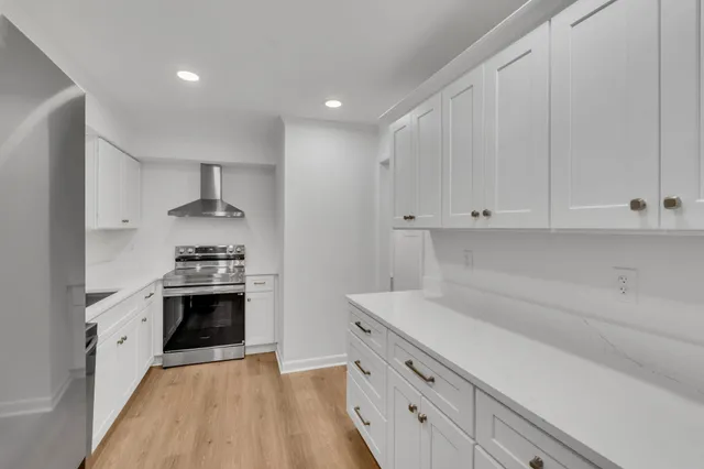a kitchen with granite countertop white cabinets and stainless steel appliances