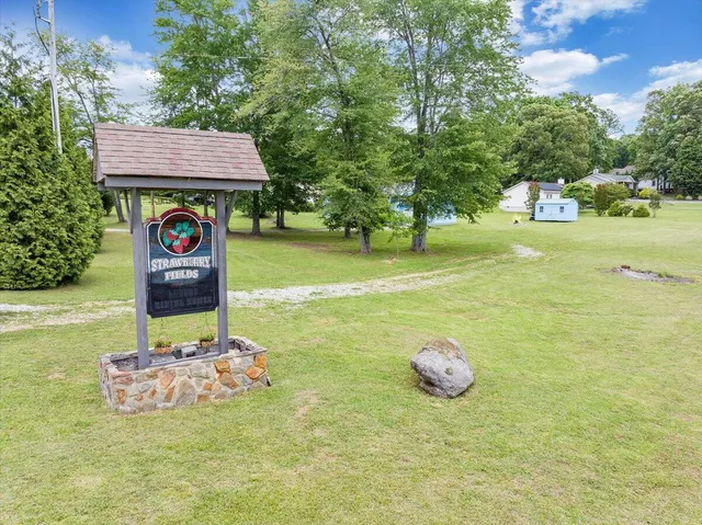 a sign that is sitting in the grass with of trees