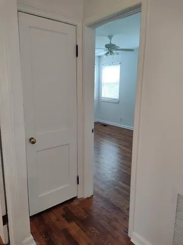 a view of an empty room with wooden floor and a window
