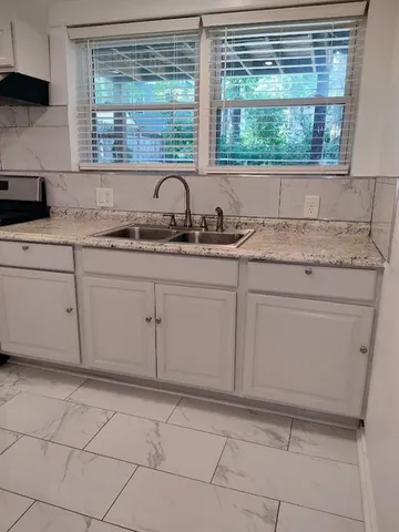 a kitchen with granite countertop a sink and a white cabinets