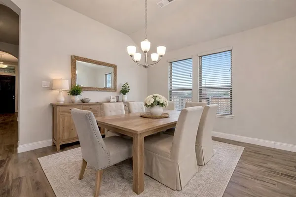 a view of a dining room with furniture a chandelier and wooden floor