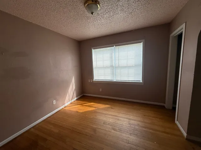 an empty room with wooden floor cabinet and windows