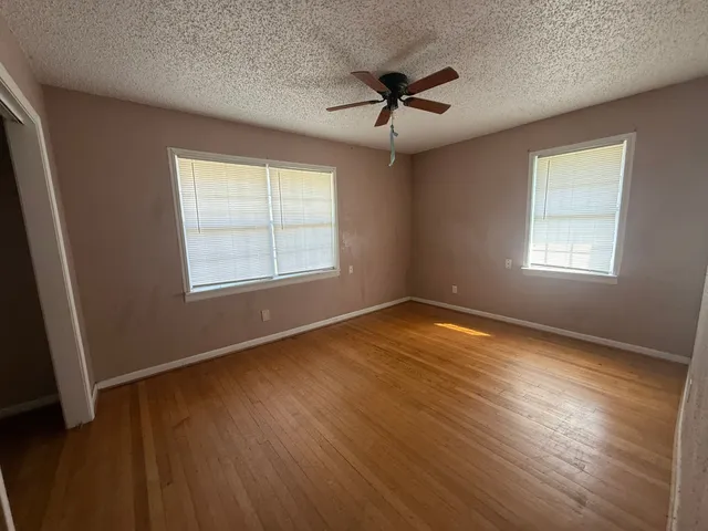 a view of empty room with wooden floor and fan