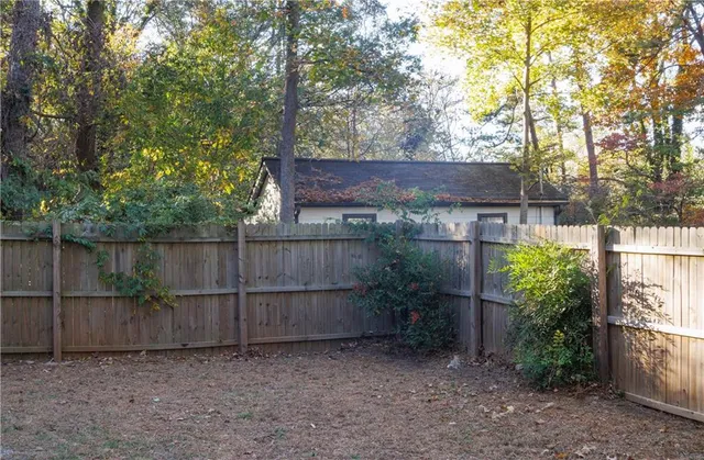 a view of a backyard with wooden fence and a large tree