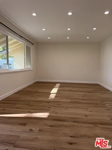 an empty room with wooden floor and large window