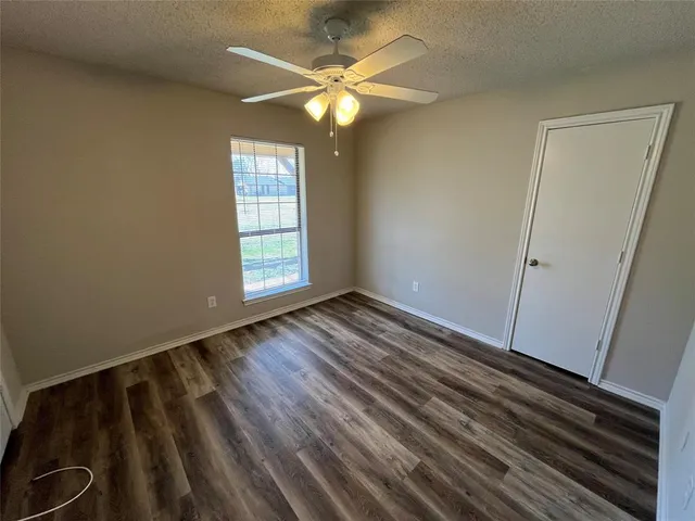 an empty room with wooden floor fan and window