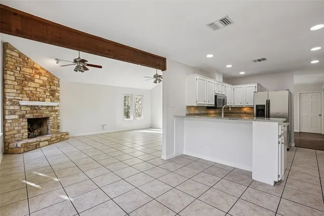 a view of open kitchen with white cabinets and refrigerator