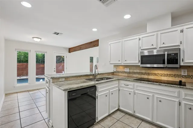 a kitchen with stainless steel appliances granite countertop a stove a sink and a microwave