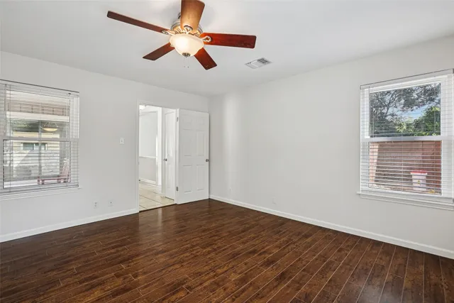a view of empty room with wooden floor and fan