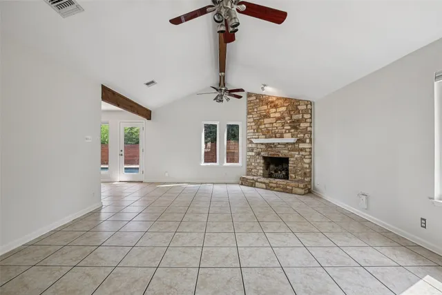 a view of an empty room with a chandelier fan and fireplace