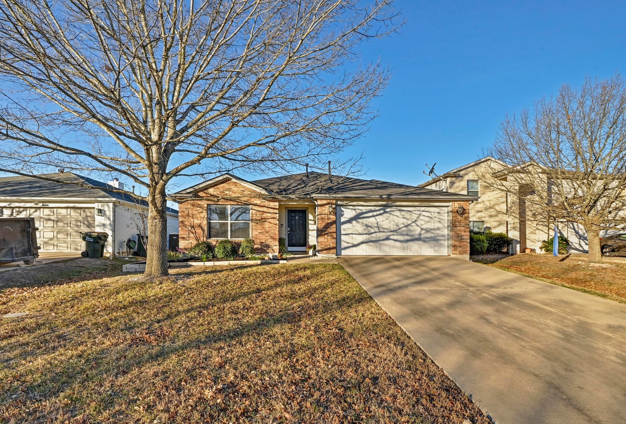 280 Spruce Drive Kyle, TX 78640 - Photo 2 of 30 Ranch-style home with concrete driveway, brick siding, a garage, and a front lawn