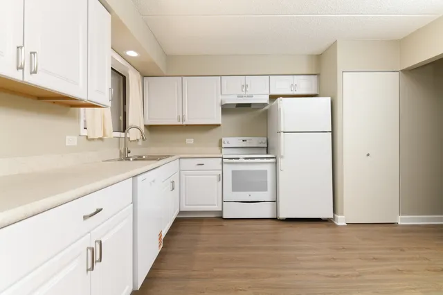 a kitchen with white cabinets and white appliances