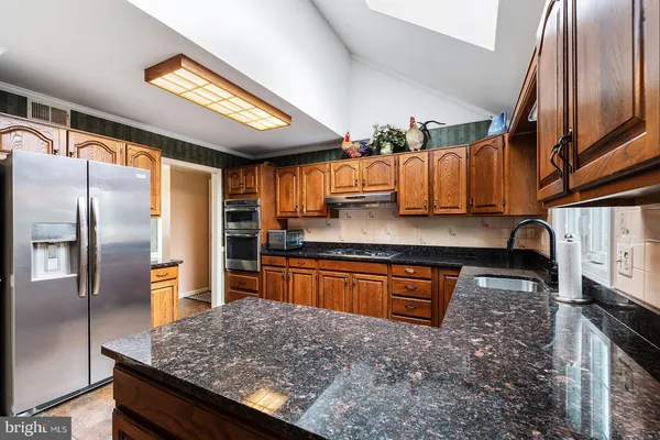 a kitchen with stainless steel appliances granite countertop a sink and a stove