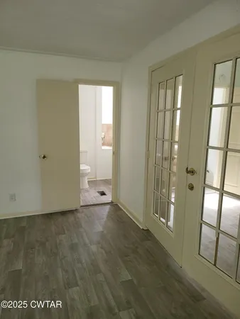 a view of an empty room with window and wooden floor