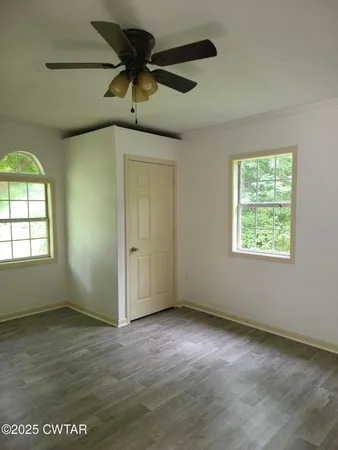 an empty room with a ceiling fan and window