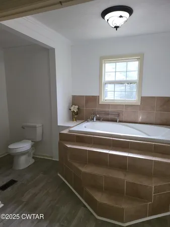a bathroom with a granite countertop sink a toilet and a window