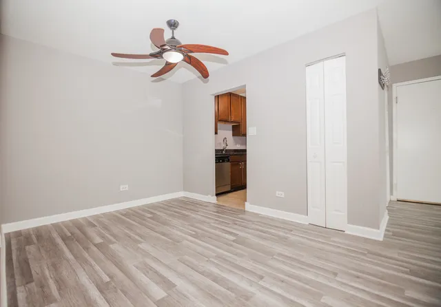 a view of empty room with wooden floor and ceiling fan