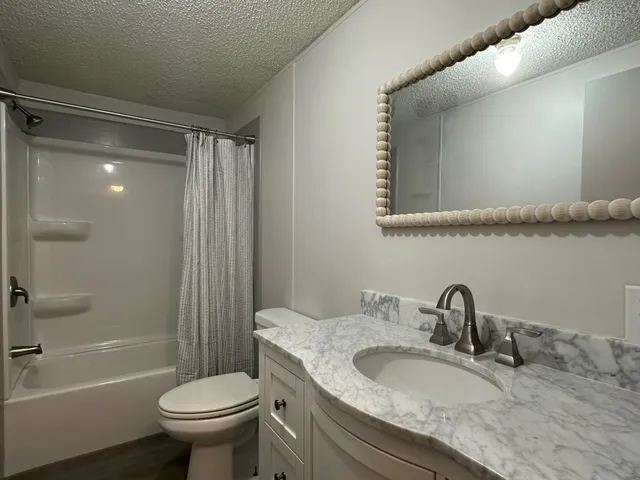 a bathroom with a granite countertop sink toilet and shower