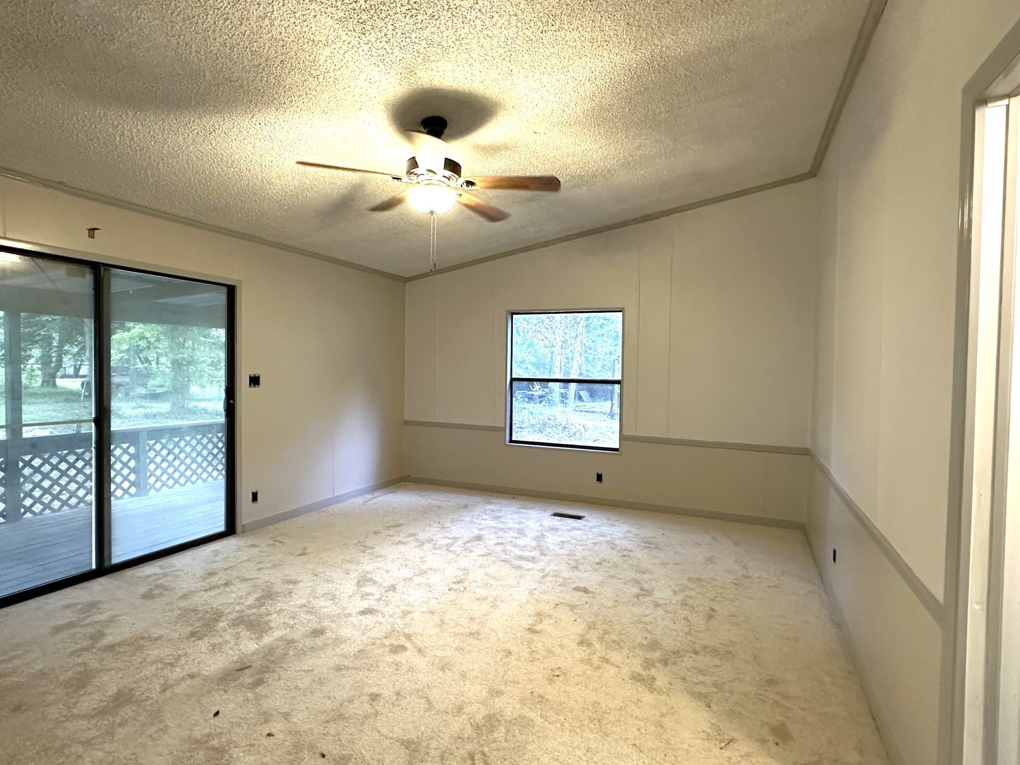 195 Charlies Lane Trinity, TX 75862 - Photo 17 of 25 en empty room with windows and chandelier fan
