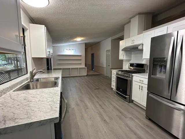 a kitchen with stainless steel appliances wooden floor sink and wooden floor