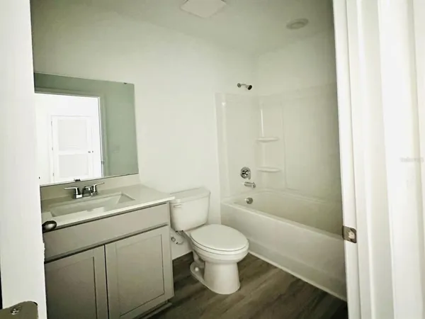 a bathroom with a granite countertop toilet a sink a mirror and shower
