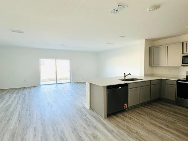 a large kitchen with wooden floor and stainless steel appliances