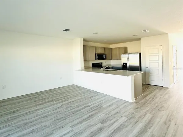 a view of a kitchen with kitchen island a sink wooden floor and living room