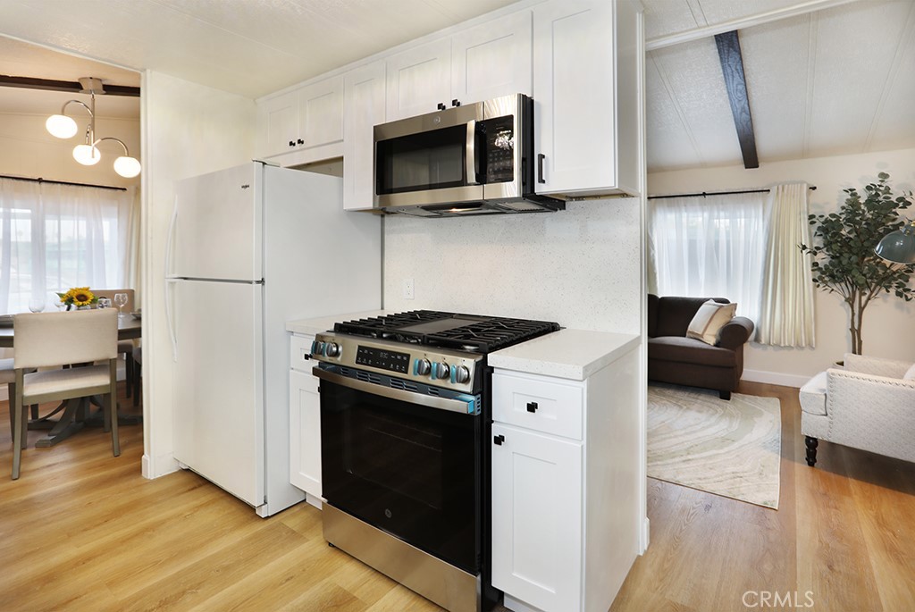 17261 Gothard Street, Unit 60 Huntington Beach, CA 92647 - Photo 7 of 27 a kitchen with stainless steel appliances a stove a microwave and cabinets